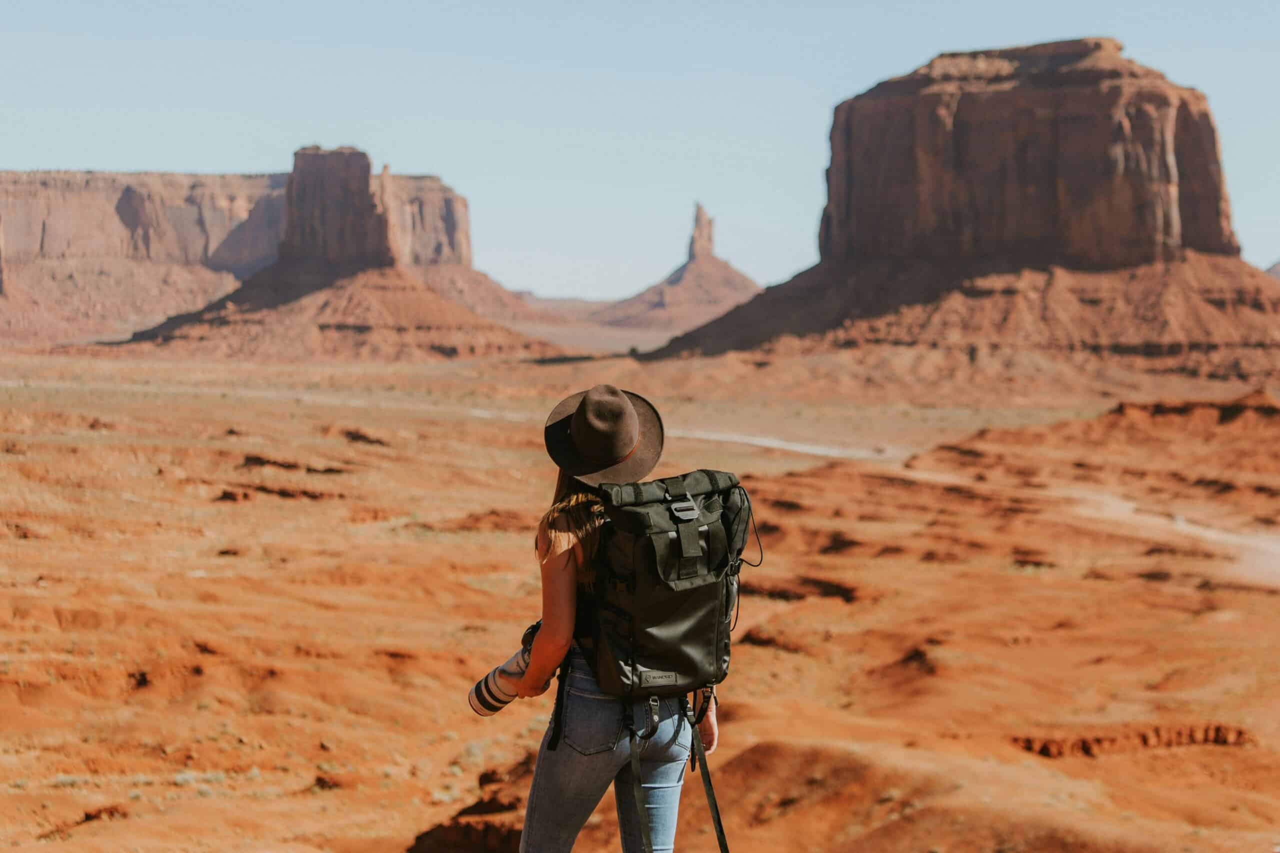 Solo traveller with a backpack looking out over Monument Valley